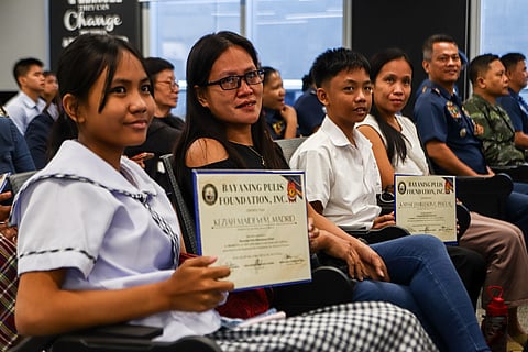 Beneficiaries of the Bayaning Pulis Foundation Inc. shows their certificates in an event hosted by the Philippine National Police in Pasay City