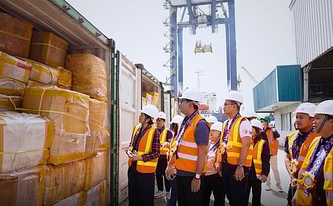 OFFICIALS from the Bureau of Customs and Department of Migrant Workers stand beside containers of abandoned balikbayan boxes during a turnover event in Davao City.