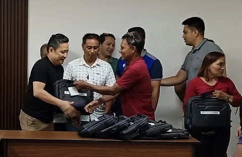GLOBE vice president for external affairs Patrick Gloria (left) distributes laptops to barangay peace officers at the turnover ceremony for the donation.