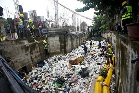 Workers from the Metropolitan Manila Development Authority gather trash by using heavy equipment as they clean the Maligaya Creek in Caloocan City on Wednesday.