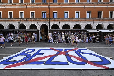 People gather to protest against the wedding of Amazon Founder and CEO Jeff Bezos and journalist Lauren Sanchez in Venice, on 13 June 2025. Poster campaigns and stickers have spread throughout the city, including one with images of Bezos reading "No space for Bezos" as some local residents protest claiming the city is transformed into a playground for billionaires.