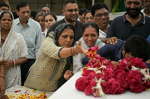 Relatives mourn near the coffins of victims, who were killed in the Air India flight crash, during a special prayer before the funeral ceremony in Ahmedabad on 15 June 2025. Grieving families held funerals in India on June 15 for their relatives who were among at least 279 killed in one of the world's worst plane crashes in decades.