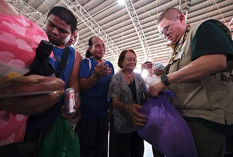 SECRETARY Francisco Tiu Laurel Jr. (right) distributes P20-per-kilo rice to residents of Siquijor during the program’s official launch on Tuesday.