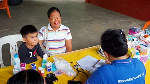John David Cabral (left) and Lenny Cabral-Anciado attend the medical mission in Nasugbu, Batangas. (Inset) One of SM Foundation’s six mobile clinics sets off from SM City Tuguegarao en route to Cagayan.