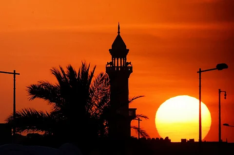 The sun sets near a mosque in Doha on June 21, 2025.