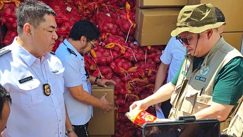 Department of Agriculture Secretary Francisco Tiu Laurel (right), assisted by Bureau of Customs Cagayan de Oro port collector Engineer Arthur Sevilla Jr., inspects the confiscated smuggled onions worth P2 million, on Tuesday at the Mindanao Container Terminal, Tagoloan, Misamis Oriental.