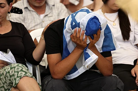 A young man covers his head with an Israeli flag as he mourns Ronel Ben-Moshe, a soldier killed in the Gaza Strip the day before, during his funeral in Rehovot on 25 June 2026. Seven Israeli soldiers were killed in Gaza after an attack on their armored vehicle, Israel said on 25 June, in one of the deadliest incidents for its forces in the more than 20-month war.