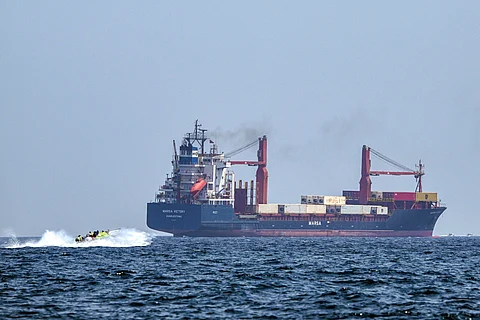A boat approaches the St Kitt's and Nevis-flagged container ship Marsa Victory while crusing in the waters of the Strait of Hormuz off the coast of Khasab in Oman’s northern Musandam peninsula on June 25, 2025.