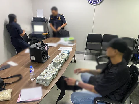 A male passenger (right, wearing a cap) was intercepted by airport authorities after being caught with P1.2 million and USD580,000 in undeclared cash at NAIA Terminal 3.
