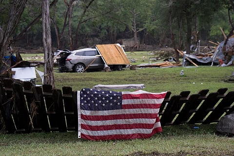 HUNT, TEXAS - JULY 06: An American flag hangs on a fence amid debris after massive flooding on July 6, 2025 in Hunt, Texas. Flash flooding from heavy rainfall on July 4 killed multiple people across central Texas.
