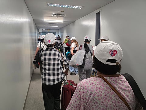 REPATRIATED Filipino caregivers from Israel walk through the airport terminal after arriving in Manila.