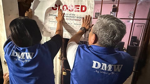 Department of Migrant Workers officials post “CLOSED” notice at a Cavite establishment found to be operating as a front for illegal recruitment, during a joint operation with local authorities on 9 July 2025.