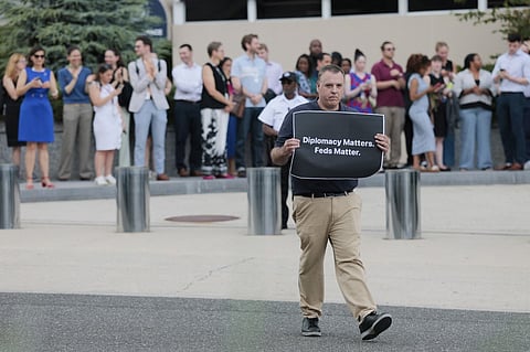 A man holds up a sign saying "Diplomacy Matters. Feds Matter" outside the Harry S. Truman Federal Building on 11 July 2025 in Washington, DC. The State Department is proceeding with layoffs just two days after the Supreme Court overturned a lower-court order that had temporarily blocked U.S. President Donald Trump's administration plan to cut federal jobs, affecting more than 1,300 department employees.