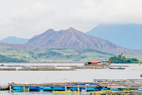 TAAL Volcano looms in the background as the Philippine Coast Guard conducts search and recovery operations off Laurel, Batangas — where the remains of the missing sabungeros were allegedly dumped. A tarped banca and an ROV assist divers facing poor visibility and harsh underwater conditions.