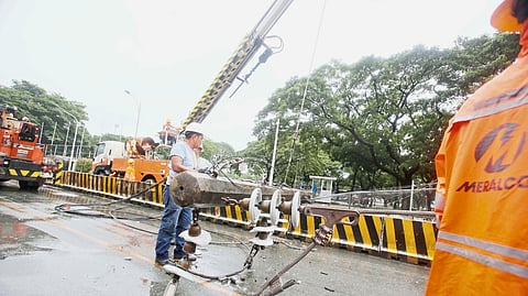 Facing nature’s fury Meralco responder clears debris, including a fallen electric post, along Katipunan Avenue in Quezon City after powerful winds from the habagat, intensified by ‘Crising’ battered Luzon.