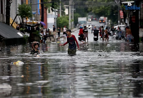 CHILDREN play and bathe in waist-deep floodwaters along Maria Clara Street in Quezon City on Saturday, 19 July 2025, as heavy rains from the southwest monsoon, intensified by Severe Tropical Storm Crising, continue to drench Metro Manila.
