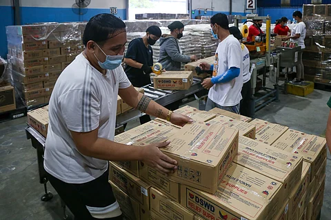 VOLUNTEERS at the DSWD-National Resource Operations Center in Pasay City prepare relief goods for areas affected by tropical storm 'Crising.' The agency has prepositioned supplies nationwide to ensure timely response.