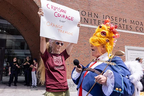 BOSTON, MASSACHUSETTS - JULY 21: A person dressed as Donald Trump interacts with a group of protestors outside of the John Joseph Moakley United States Courthouse on July 21, 2025 in Boston, Massachusetts. Lawyers for Harvard University argued in federal court on Monday that the federal government's freeze of more than $2 billion in grants and contracts is illegal and should be reversed.