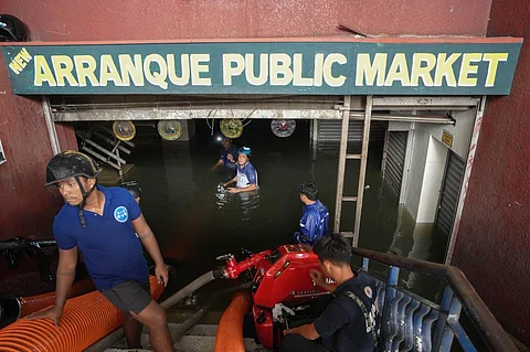 Workers from the local government of Manila prepare the water suction machine to pump out floodwater from the Arranque Market which was submerged following non-stop rains due to the storm and southwest monsoon.