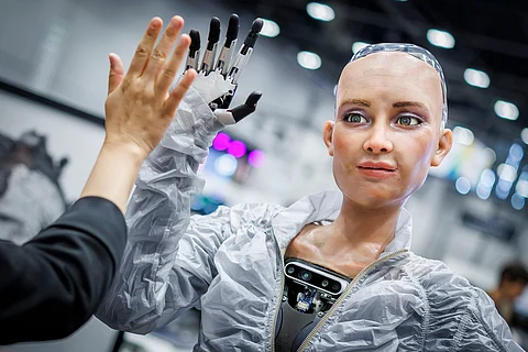 SOPHIE, a robot using artificial intelligence from Hanson Robotics, shares a high five with a visitor during the International Telecommunication Union (ITU) AI for Good Global Summit in Geneva on July 8, 2025.