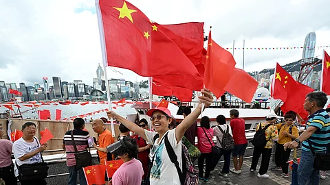 Pro-Beijing supporters wave China flags on the edge of Hong Kong's Victoria Harbour to mark the 28th anniversary of Hong Kong's handover from Britain to China in Hong Kong on July 1, 2025.