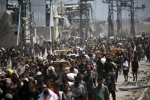 PALESTINIANS return to the Nuseirat refugee camp from a United States-backed Gaza Humanitarian Foundation distribution point near the Netsarim corridor in the central Gaza Strip, some carrying food parcels and others wooden pallets for burning, on 27 July 2025.