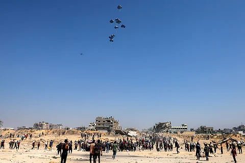 PALESTINIANS gather as a C-130 Hercules military transport aircraft drops humanitarian aid on the northern Gaza Strip on 27 July 2025.