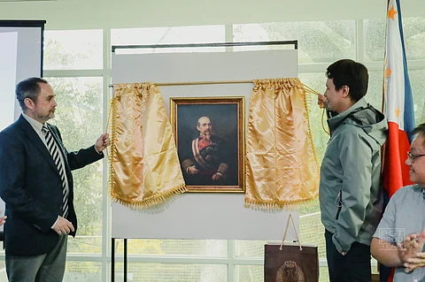 HISPAULT President Engineer Jose Antonio Portillo Corpas and Tarlac Governor Christian Tell Yap pose beside the painting of Spanish General Juan Alaminos y Vibar at the Carlos P. Romulo Library in Tarlac City.