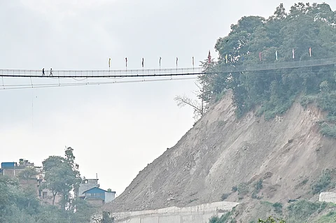 PEOPLE walk across a footbridge at a landslide-prone area near the Arniko Highway in Nepal’s Kavre district.