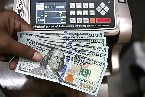 A worker holding US dollar banknotes poses for a photograph at a money exchange outlet in New Delhi on July 31, 2025. On July 30, two days before the deadline for the reintroduction of Trump's so-called "reciprocal tariffs", the US president announced that Indian shipments to the United States would be hit with a 25 percent tariff.