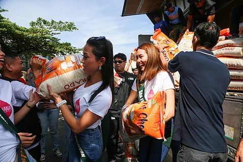 MISS Earth candidates Ellamarie Andricoso (right) representing San Fernando, Bukidnon and Maria Erra Ocon representing Impasug-ong, Bukidnon help distribute bags of rice to residents of Bani, Pangasinan.