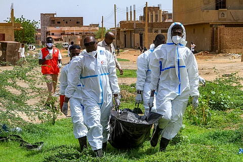 Members of the Sudanese Red Crescent carry in a bag the exhumed remains of a person from a makeshift grave for reburial in the local cemetery in Khartoum's southern suburb of al-Azhari on August 2, 2025 after the dead were buried in a rush when the area was under control of the Rapid Support Forces (RSF) paramilitaries. In Sudan's war-scarred capital Khartoum, Red Crescent volunteers have begun the grisly task of exhuming the dead from makeshift plots where they were buried during the fighting so their families can give them a proper funeral.