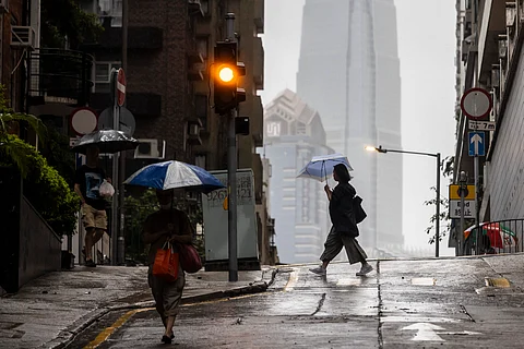 People use umbrellas to protect themselves from the rain in Hong Kong on August 14, 2025, as Typhoon Podul weakens to a severe tropical storm.