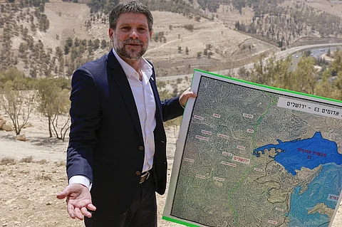 Israeli far-right Finance Minister Bezalel Smotrich holds a map of an area near the settlement of Maale Adumim, a land corridor known as E1, outside Jerusalem in the occupied West Bank, on August 14, 2025, after a press conference at the site. Israel's finance minister on August 14 backed plans to build 3,400 homes in a contentious area of the occupied West Bank, calling for the territory's annexation in response to several countries announcing plans to recognise a Palestinian state.
