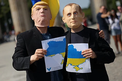 BERLIN, GERMANY - AUGUST 14: Activists dressed as U.S. President Donald Trump (L) and Russian President Vladimir Putin pose after ripping up a map of Ukraine at a demonstration in front of the Brandenburg Gate on August 14, 2025 in Berlin, Germany. The small group of protesters were urging Trump not to sell out Ukraine at talks between him and Putin towards ending Russia's war in Ukraine scheduled for tomorrow in Alaska.