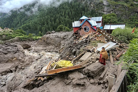 A woman looks on as she stands near a damaged house at the site of a flashflood at a village in Kishtwar district on August 15, 2025. Indian rescuers pulled bodies from mud and rubble August 15 after the latest deadly flood to crash through a Himalayan village killed at least 60 people and washed away dozens more.