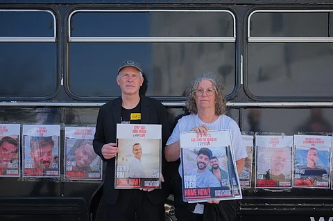 Former Israeli hostages Keith Siegel (L) and his wife Aviva (R) hold posters of Israelis currently held hostages in the Gaza Strip at a pro-Israel demonstration, a bus ride to the Red Cross headquarters calling to “Bring the Hostages Home” with former hostage”, organized by the South African Zionist Federation (SAZF) in Johannesburg on August 18, 2025. After Hamas stormed kibbutz Kfar Aza on October 7, 2023 the couple were held hostage in the Gaza Strip, Keith Siegel for 484 days and his wife Aviva for 51 days.