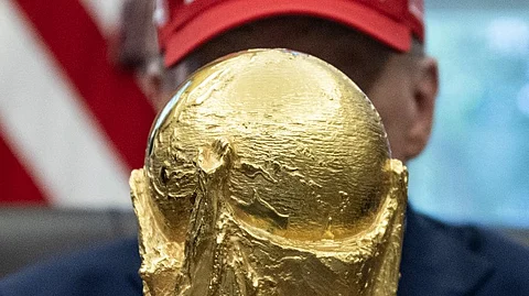 US President Donald Trump holds the World Cup trophy in the Oval Office of the White House in Washington, DC, on August 22, 2025. Trump announced the 2026 World Cup draw will be held on December 5 at Washington's Kennedy Center.