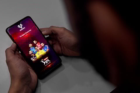 In this photo illustration taken on October 12, 2020, a user checks the Dream11 application of the Indian Premier League (IPL) cricket tournament, on his mobile phone in New Delhi. India's parliament has passed a sweeping bill banning online gambling, after government figures showed companies had stripped $2.3 billion annually from 450 million people.