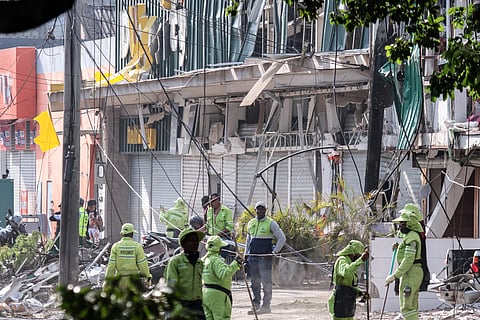Garbage services workers collect debris in the area of a bomb explosion in Cali, Colombia on August 22, 2025. Six people were killed and dozens more injured when a truck loaded with explosives was detonated on a busy street near a military aviation school in Cali on August 21, 2025, Colombian authorities said.