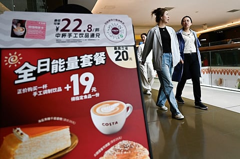 Women walk past a branch of the Costa cafe in Beijing on 8 May 2025. The coffee chain operates 3,000 stores outside the UK but is reportedly being put up for sale by Coca-Cola