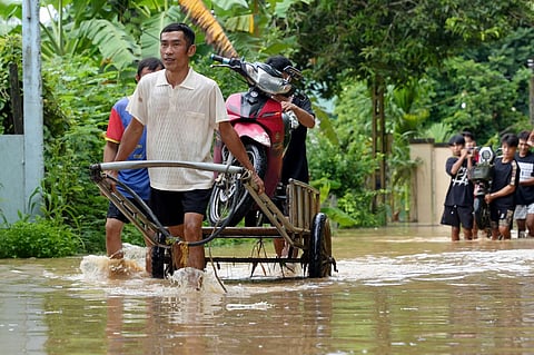 People transport motorbikes through flooded areas in Vietnam's north-central Nghe An province on July 23, 2025, following heavy rains brought by Tropical Storm Wipha.