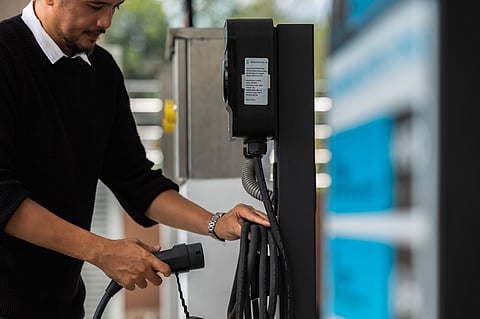 A DRIVER carefully sets up at an ACMobility charging station, showing how proper handling of cables and equipment makes EV charging safe and easy in any weather.
