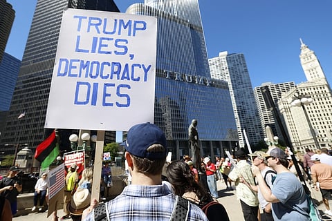 Protesters hold signs reading "Trump lies, Democraty dies" during a rally outside Trump Tower on Labor Day in Chicago, Illinois, September 1, 2025.