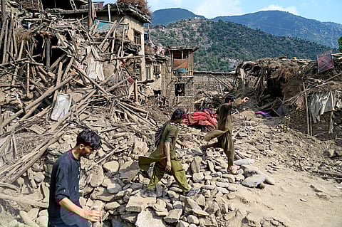 Afghans walk past damaged houses, after earthquakes at Mazar Dara village in Nurgal district, Kunar province, in Eastern Afghanistan, on September 1, 2025. More than 800 people have died and over 2,700 were injured from August 31 night to September 1, 2025, in eastern Afghanistan after a 6-magnitude earthquake, followed by at least five aftershocks felt hundreds of kilometers away.
