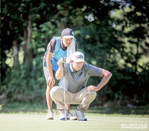 KEANU Jahns reads the line of his putt on his way to sharing the lead in the ICTSI Bacolod Challenge at the Bacolod Golf and Country Club on Wednesday.