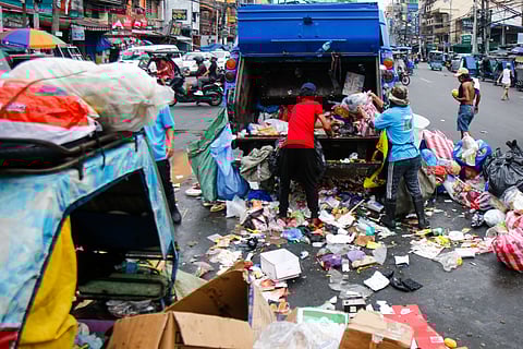 SANITATION workers collect garbage along Moriones Street in Tondo, Manila.
