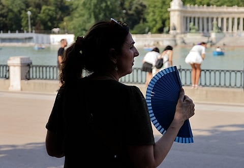 A woman uses a hand fan in a park during the first heatwave of the summer in Madrid, on June 28, 2025. Starting June 28, 2025 southern Europe will once again face extreme temperatures exceeding 40°C. Scientists warn that periods of extreme heat will become longer, more frequent and more intense as human-induced climate change accelerates.