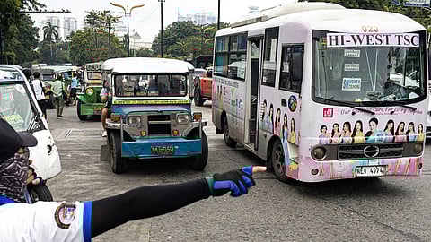 A traffic enforcer directs traffic during the staging of the transport strike organized by Manibela and Piston. The protest will run for three days.
