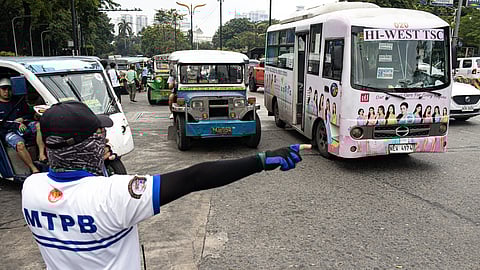 A traffic enforcer directs traffic during the staging of the transport strike organized by Manibela and Piston. The protest will run for three days.